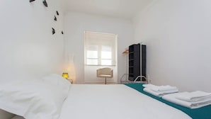 Una habitación de hotel con cama, una silla, armario y ventana.