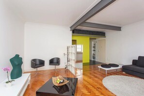 A modern living room with a black sofa, two black chairs, a white coffee table, and a decorative green bust.