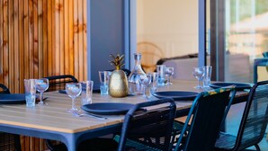Une table à manger dressée avec de la vaisselle transparente, un ananas en guise de centre de table et des chaises noires.