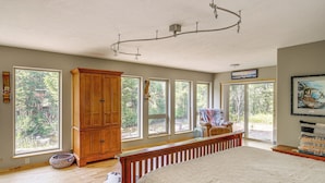 Amplia habitación con una cama grande, armario de madera y varias ventanas que ofrecen vistas al exterior.
