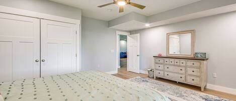 A bedroom with a bed, a dresser, a mirror, and a ceiling fan.