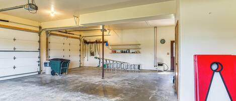A garage with a concrete floor, a green utility cart, and a red storage box with a logo.