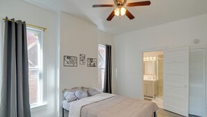 A bedroom with a bed, a ceiling fan, and a bathroom visible through an open door. - Walk to Churchill Downs: Pet-friendly Retreat! (Louisville)