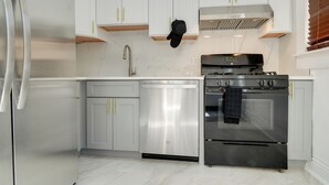 A modern kitchen with stainless steel appliances, white cabinetry, and a black oven mitt hanging on the wall. - Walk to Churchill Downs: Pet-friendly Retreat! (Louisville)