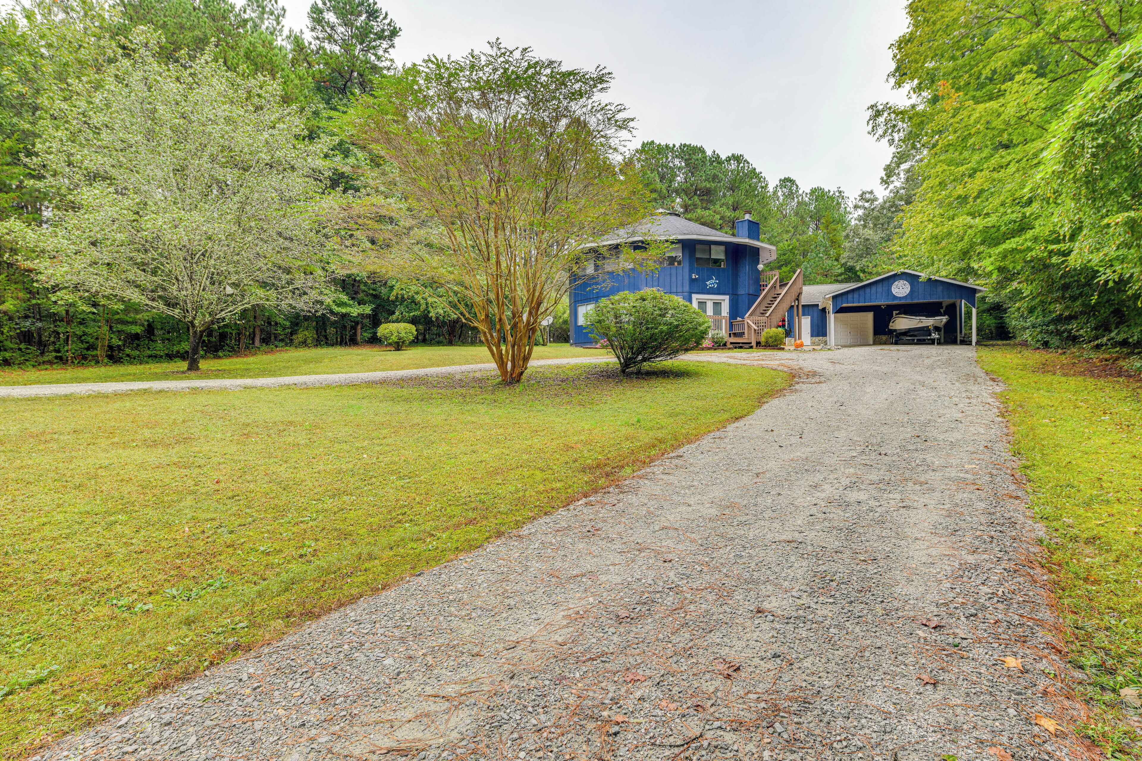 A gravel driveway leading to a blue house with a garage.