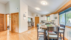 Une cuisine spacieuse avec des meubles en bois, un coin repas comprenant une table et des chaises, et une vue dégagée grâce à de grandes fenêtres.