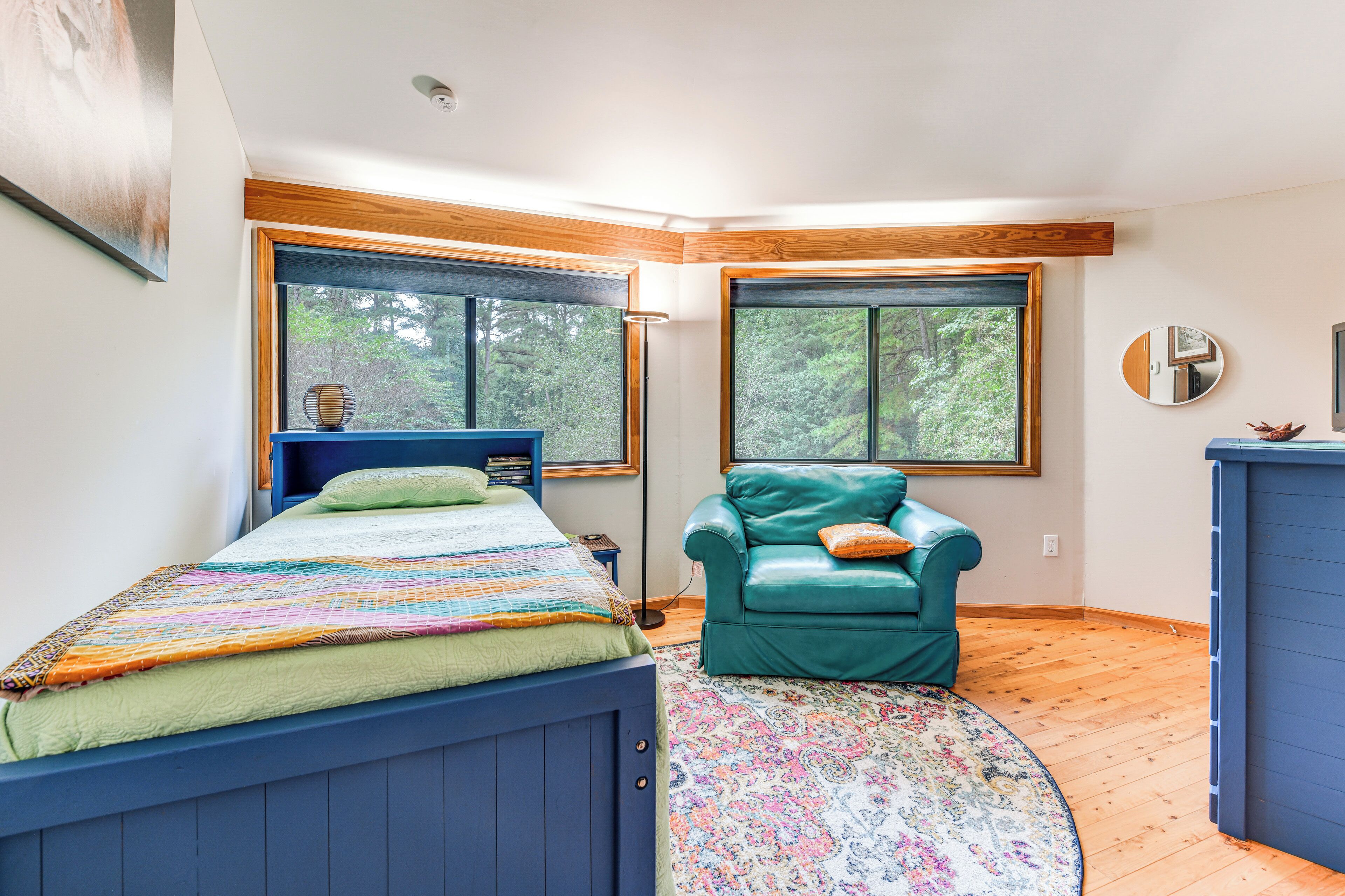 Ein Schlafzimmer mit einem Bett, einem grünen Ledersessel und großen Fenstern.