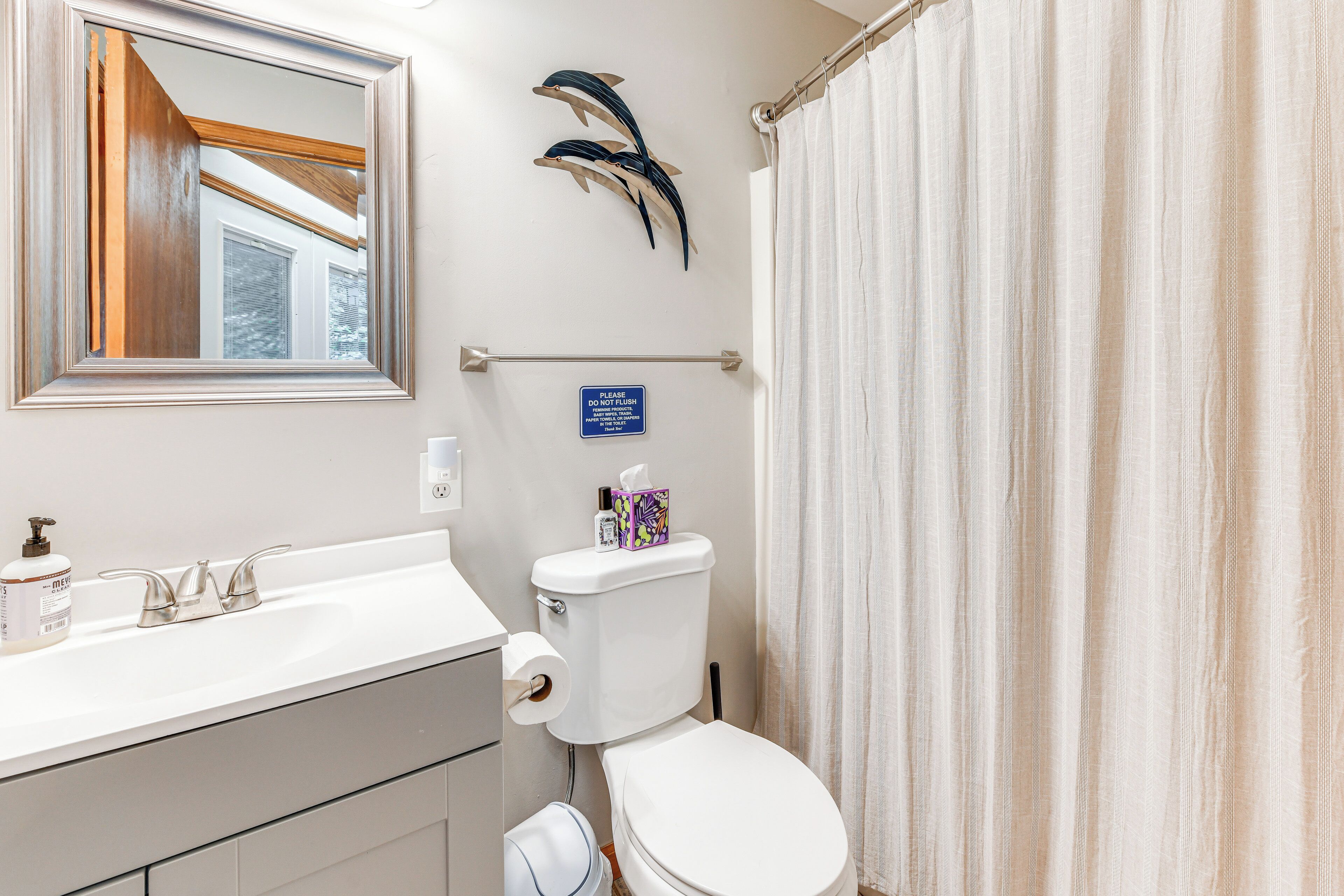 Un baño con lavamanos blanco, inodoro, espejo y cortina de ducha.