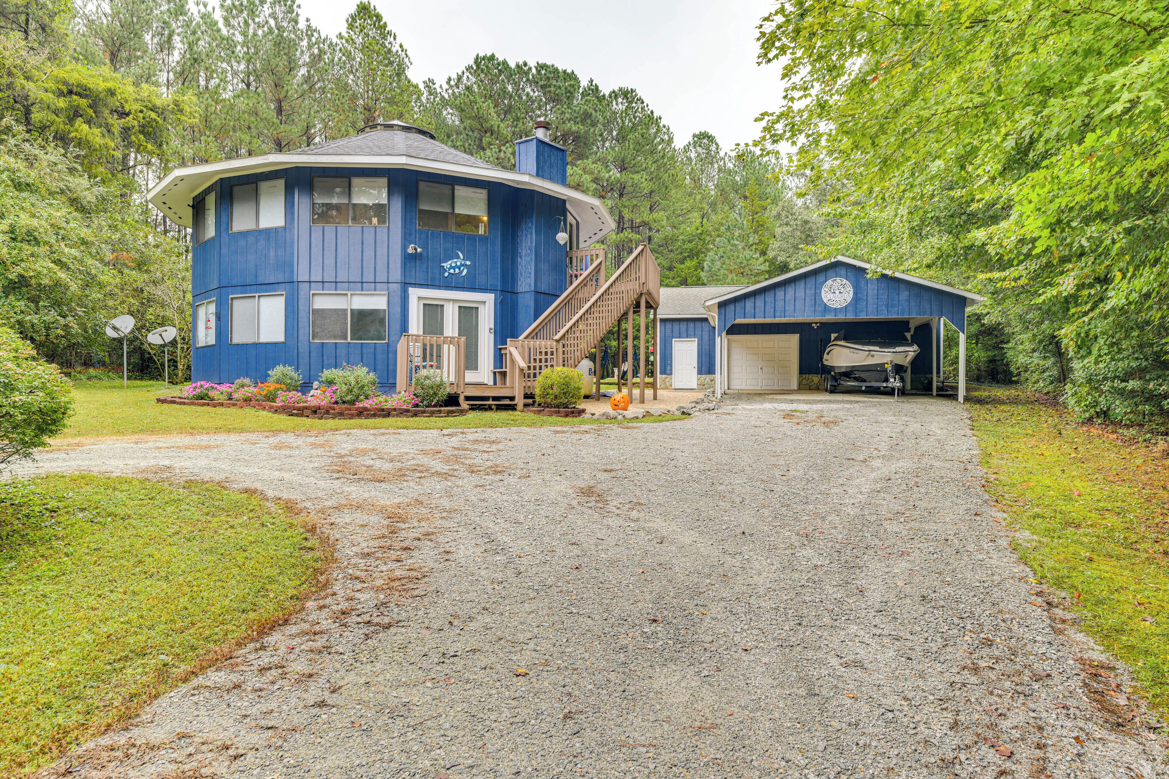 A two-story blue house with a covered porch, a gravel driveway, and a garage.