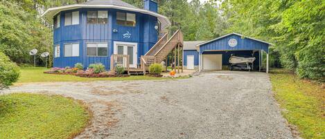 A two-story blue house with a covered porch, a gravel driveway, and a garage.