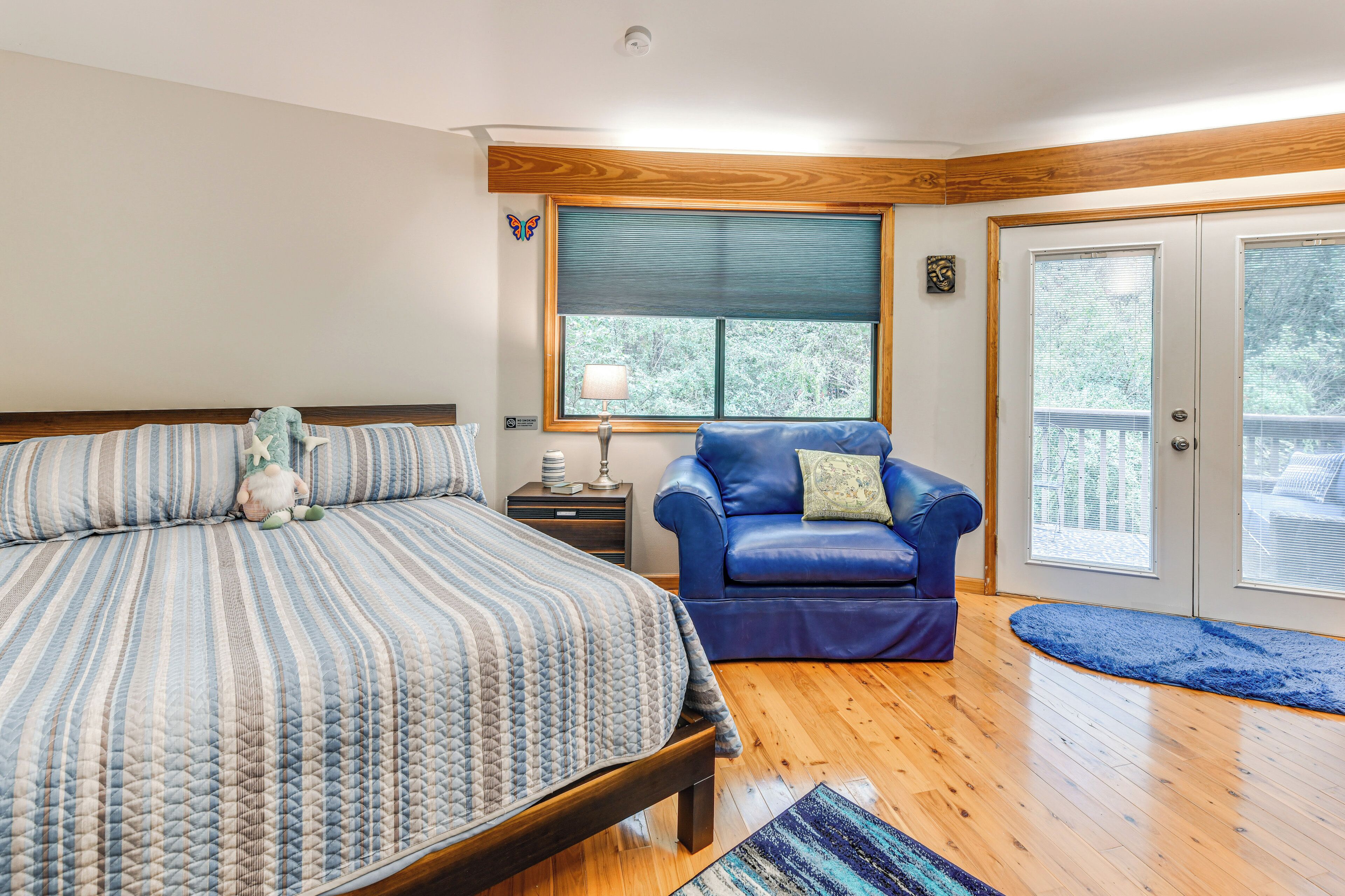 A bedroom with a bed, a blue leather chair, a window, and a door.