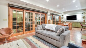 A living room with a grey sofa, wooden sliding doors, a TV, and a dining area with a table and chairs. - Scenic Getaway w/ Fire Pit & Grill in Columbia! (Columbia)