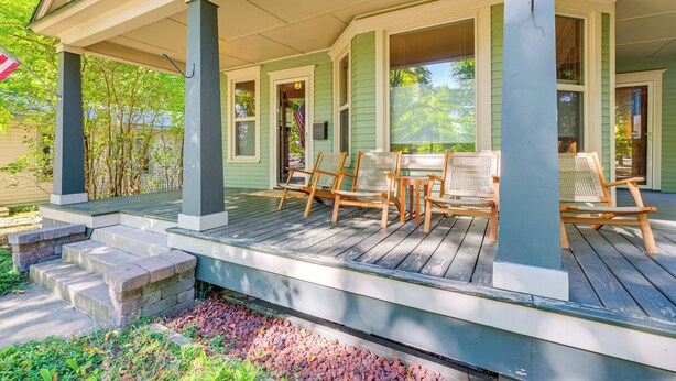 A porch with wooden chairs and a table, steps leading up to the porch, and a view of the house in the background. - Near Lake: Historic Boyne City Home w/ Fire Pit! (Boyne City)