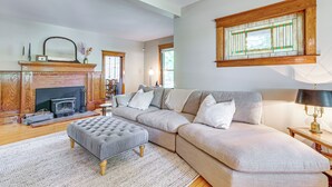 A living room with a fireplace, a sofa, and a lamp. - Near Lake: Historic Boyne City Home w/ Fire Pit! (Boyne City)