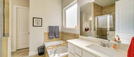 Un baño moderno con bañera, un espejo grande y un tocador con lavamanos.