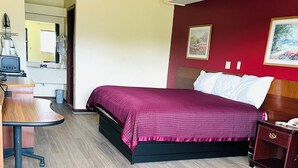 Et hotelværelse med en seng, et skrivebord og en stol.