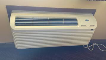 Een witte airconditioningunit bevestigd aan een muur, met een bedieningspaneel bovenop.