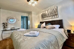 Relax in a stylish bedroom with a large bed, round mirror, and abstract art.