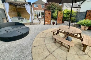 Relax on the patio with a comfortable sofa and picnic table, surrounded by a pergola and decorative metal panels.