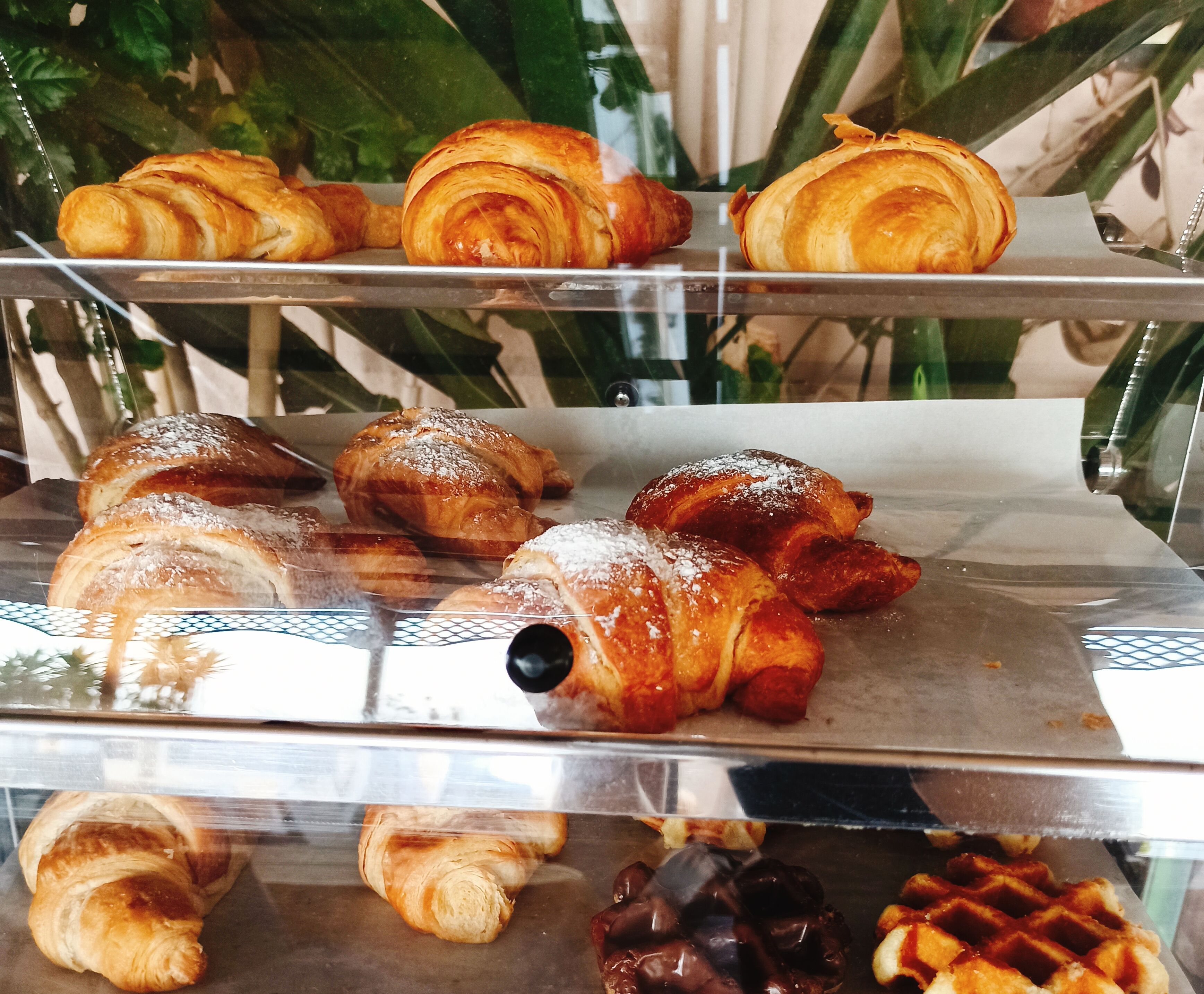 A display case with various pastries, including croissants and chocolate-covered items.