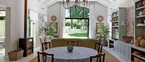 A spacious room with a round table, chairs, a sofa, and a fireplace.