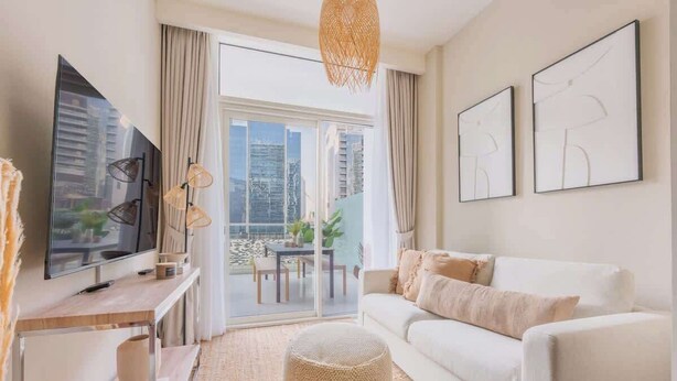 Een moderne woonkamer met een bank, een televisie en kunstwerken aan de muur.