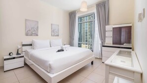 Ein modernes Hotelzimmer mit einem großen Bett, einem Schreibtisch mit Computer und einem Fenster mit Vorhängen.