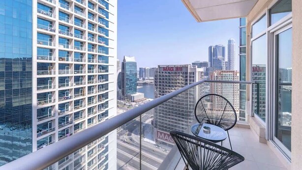 Ein Balkon mit Blick auf eine Stadtlandschaft, mit modernen Gebäuden und blauem Himmel.