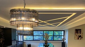 A modern dining area with a black marble island, a chandelier, and a view of the outdoors through large windows. - Empire Villa 2 Mon Plaisir (Paramaribo)