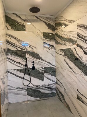 A shower area with marble tiles and a handheld showerhead. - Empire Villa 2 Mon Plaisir (Paramaribo)