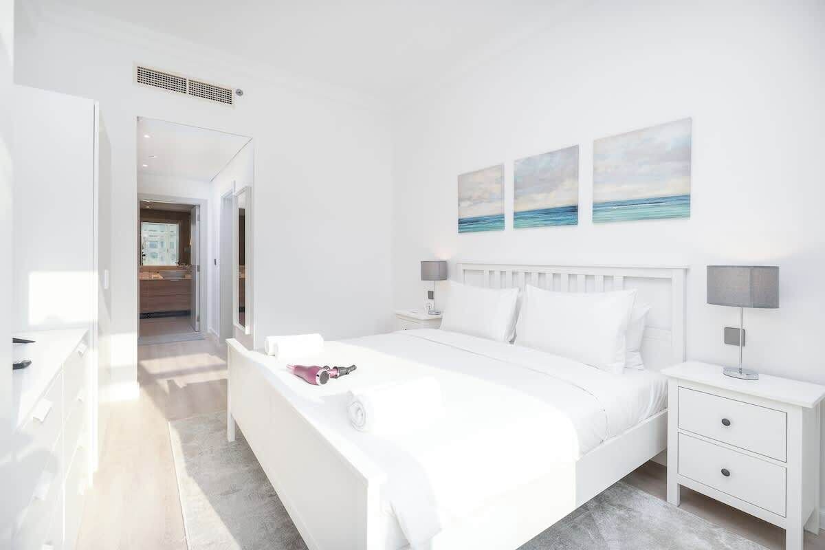 Ein modernes Schlafzimmer mit einem großen Bett, Nachttischen und Kunstwerken an der Wand.