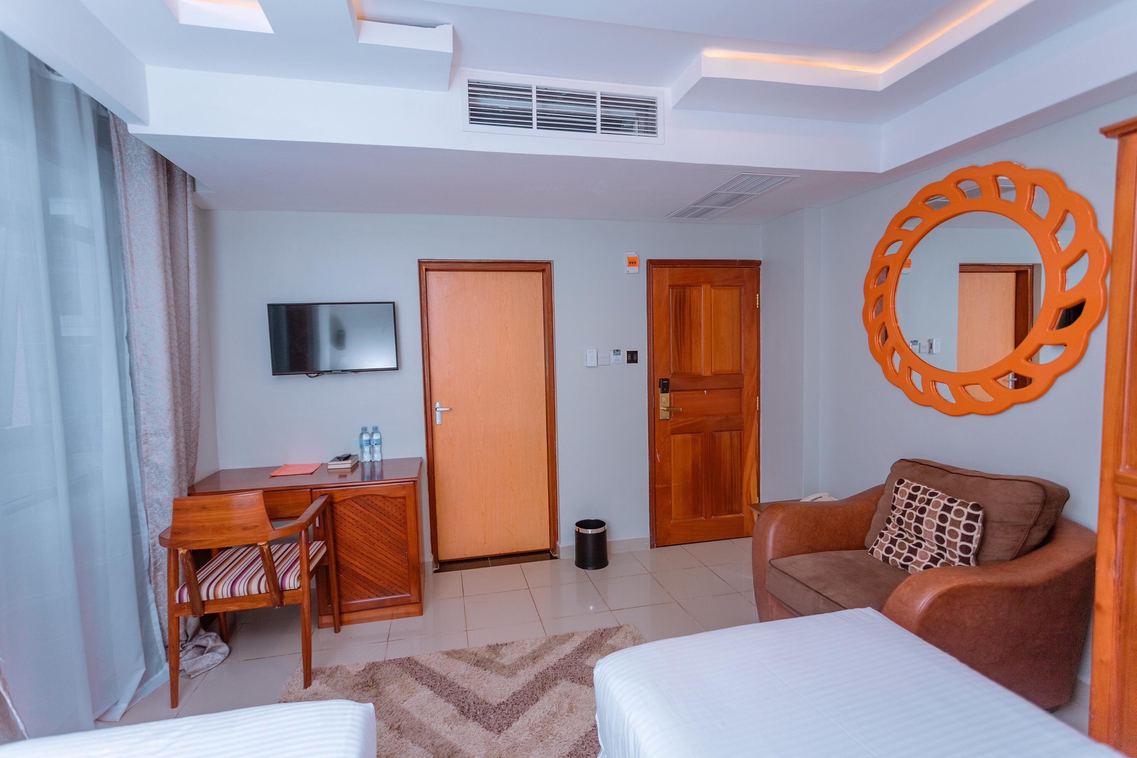 A hotel room with a bed, a desk, a TV, a sofa, and a mirror.