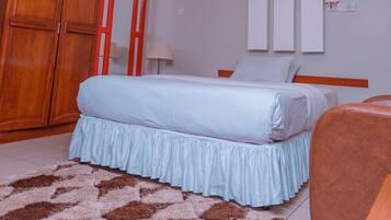 Una habitación de hotel moderna con una cama, un armario de madera, un espejo e iluminación empotrada en el techo.