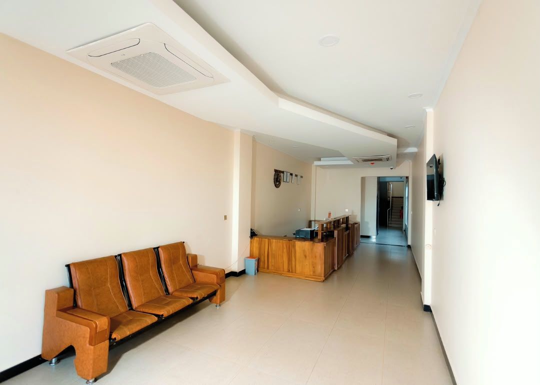 Zona de recepción con mostrador de madera, un sofá y un pasillo que conduce a otra habitación.