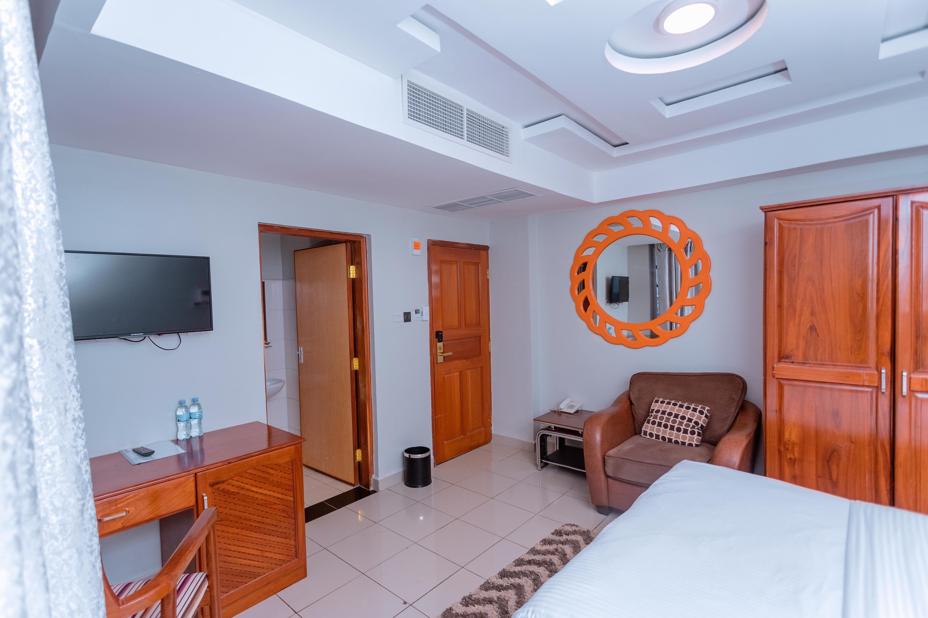 A hotel room with a bed, a desk, a chair, a TV, and a wardrobe.