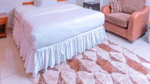 Ein modernes Hotelzimmer mit einem großen Bett, einem Sofa, einem Spiegel und einer Deckenleuchte.