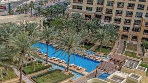 A resort with a central swimming pool surrounded by palm trees and sun loungers. - StayShort - Superb 3BR in Palm Jumeirah With Unmatched Views! (Marina/JBR)