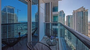 Un balcón moderno con barandas de vidrio, que ofrece vistas a edificios altos y una obra en construcción.