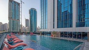 Una piscina con arquitectura moderna y rascacielos al fondo.