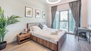 Un dormitorio moderno con una cama grande, un escritorio y vistas a la ciudad.