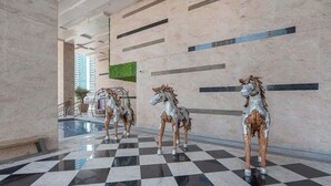 Un vestíbulo con piso a cuadros y tres estatuas de caballos.