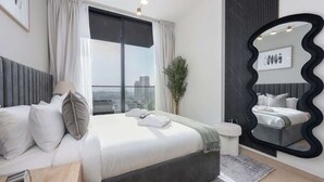 Una camera da letto moderna con un ampio letto, vista sulla città, uno specchio nero particolare e un arredamento in stile minimalista.