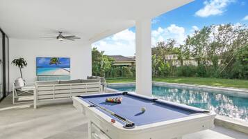 Relax by the pool with a clear view of the lush landscape, featuring a pool table and comfortable seating.