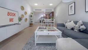 Een moderne woonkamer met een bank, salontafel en een televisie waarop 'BOOK ME' staat.