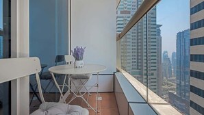 Een balkon met een kleine tafel, een stoel en een plant in een pot.