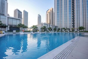 Una piscina con sillas de descanso y un edificio moderno al fondo.