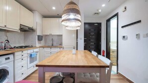 Een moderne keuken met witte kasten, een houten tafel en een hangende lamp.