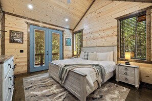 A wooden cabin bedroom with a bed, bedside table, and dresser. - Pop's Place, Pet Friendly, Hot Tub, Play Set, Firewood, and More! (Broken Bow)