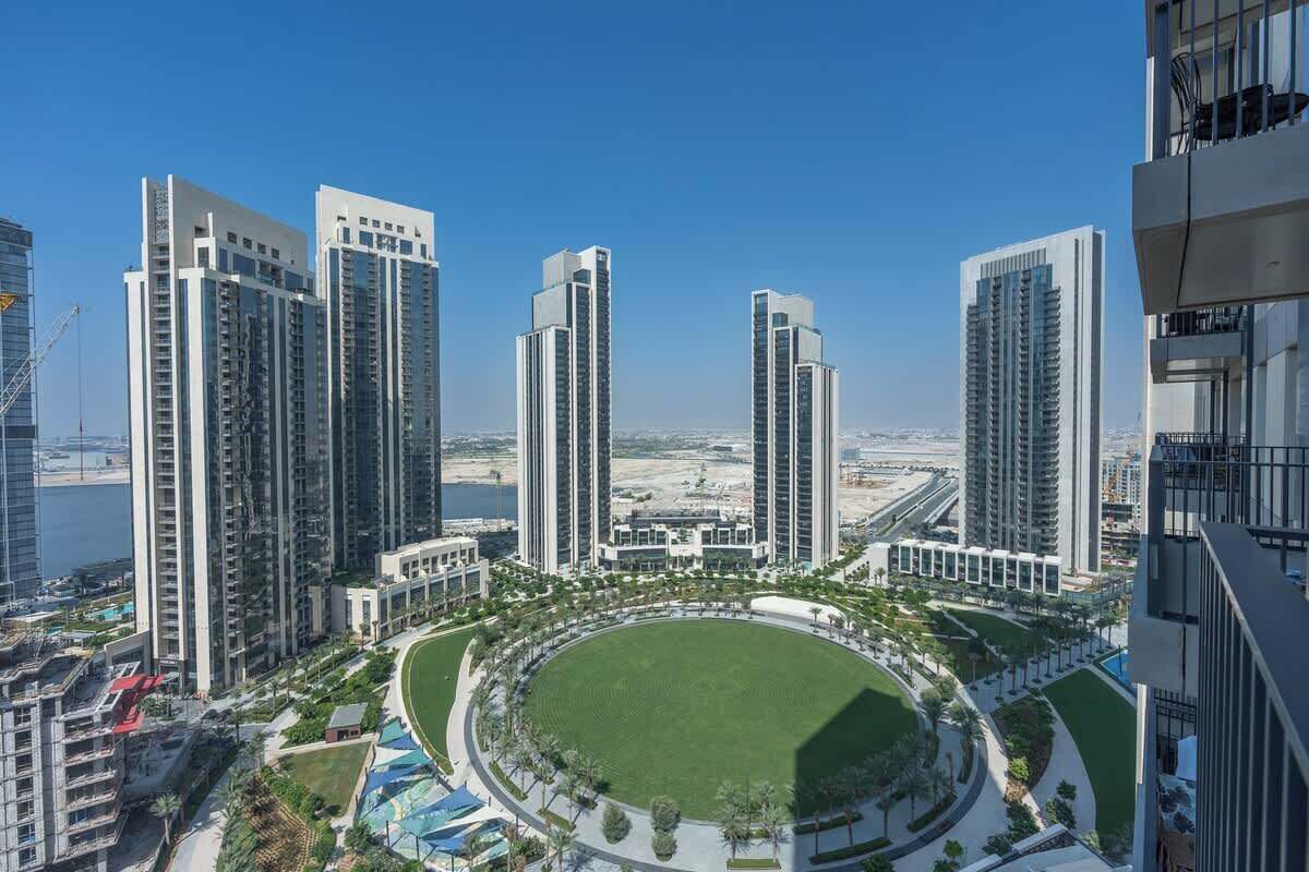 Un ensemble immobilier résidentiel composé d’immeubles de grande hauteur, de plusieurs tours, d’un espace vert circulaire central et offrant une vue sur la côte.