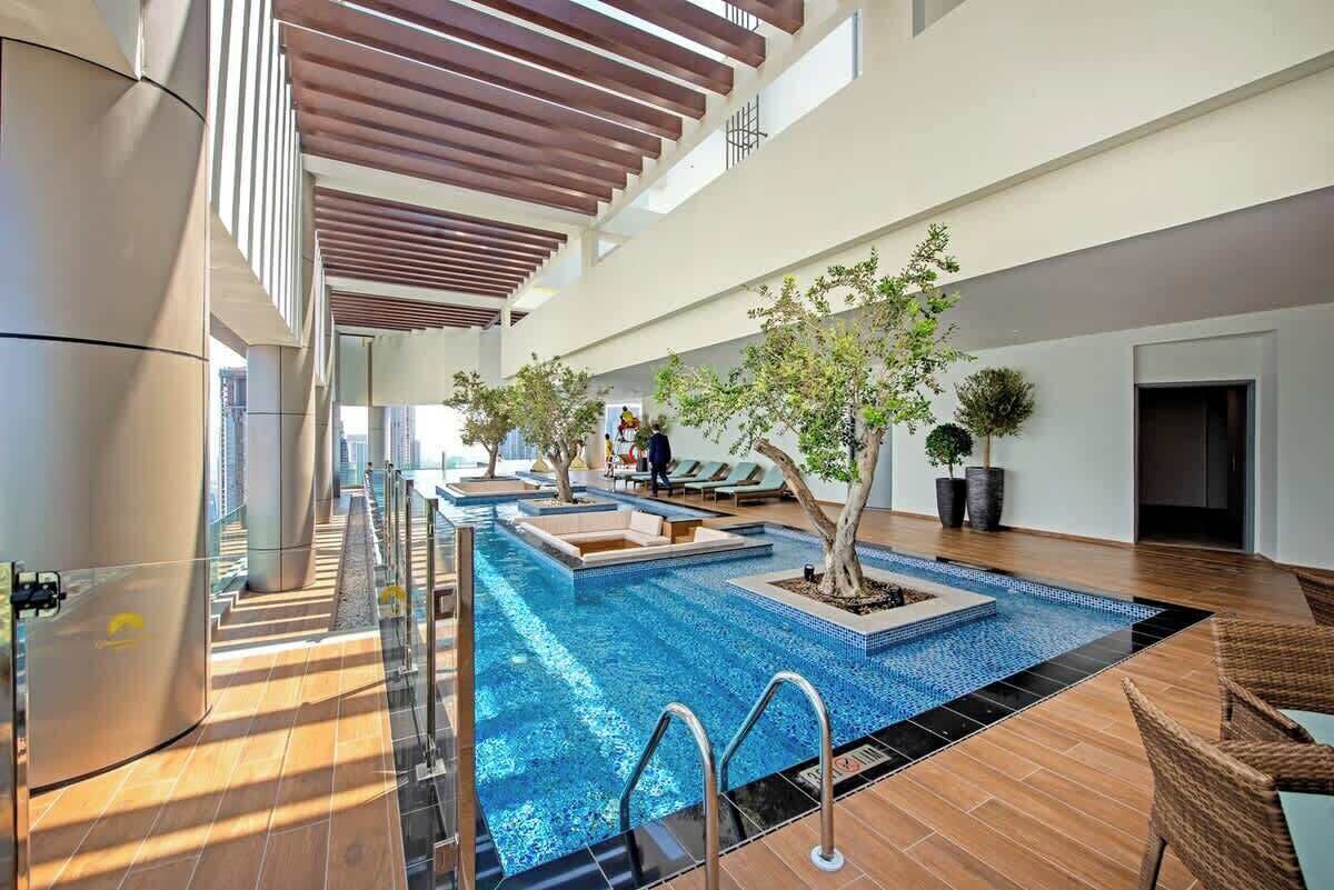 Une piscine intérieure au design moderne, entourée d’espaces de détente et agrémentée de plantes en pot.
